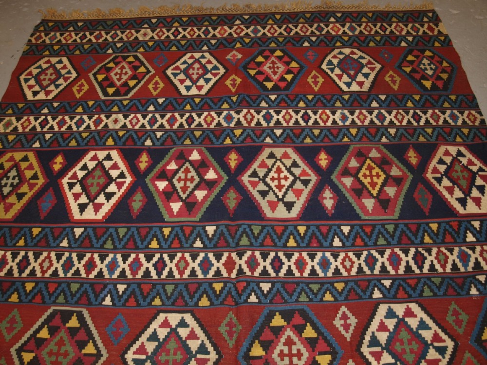 A large flat-woven antique Caucasian Shirvan kilim rug featuring horizontal bands of geometric diamond motifs in red, navy blue, green, and yellow. View II