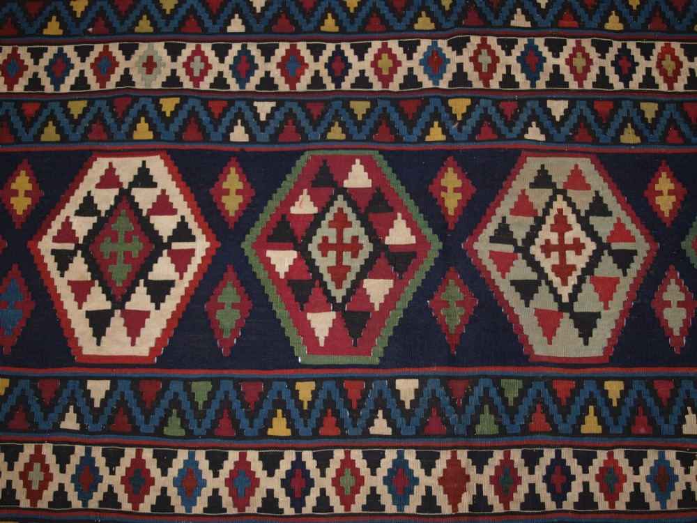 A large flat-woven antique Caucasian Shirvan kilim rug featuring horizontal bands of geometric diamond motifs in red, navy blue, green, and yellow. View VI
