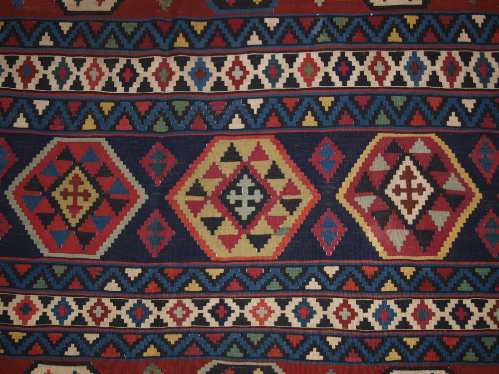 A large flat-woven antique Caucasian Shirvan kilim rug featuring horizontal bands of geometric diamond motifs in red, navy blue, green, and yellow. View VII