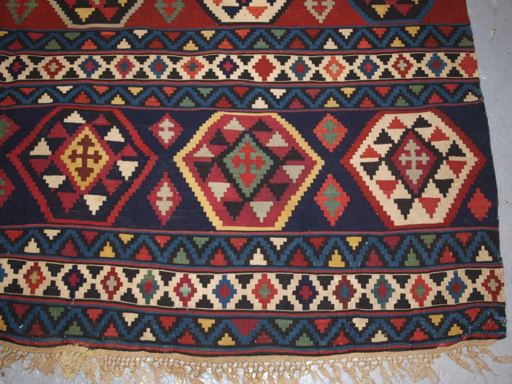 A large flat-woven antique Caucasian Shirvan kilim rug featuring horizontal bands of geometric diamond motifs in red, navy blue, green, and yellow. View IX