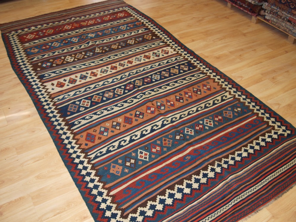 An antique handwoven Persian Varamin kilim rug featuring horizontal bands of blue, terracotta, and cream with repeating geometric diamond motifs. View II