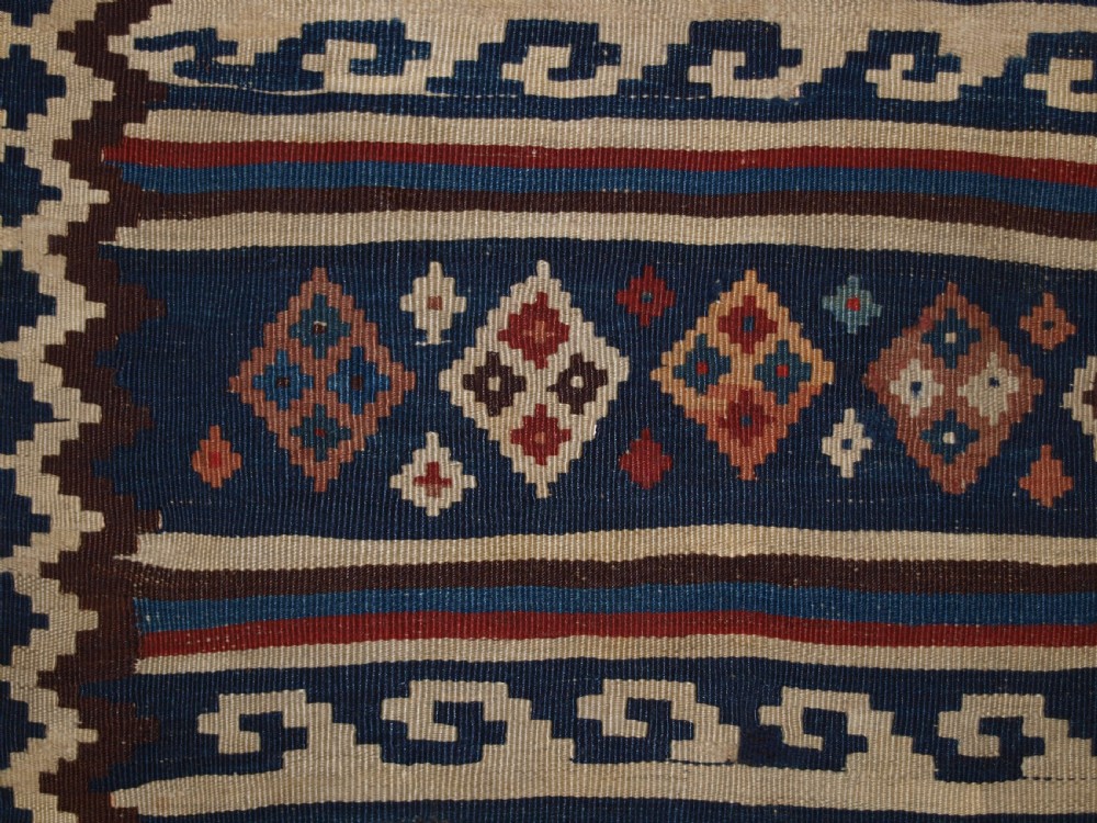 An antique handwoven Persian Varamin kilim rug featuring horizontal bands of blue, terracotta, and cream with repeating geometric diamond motifs. View XI