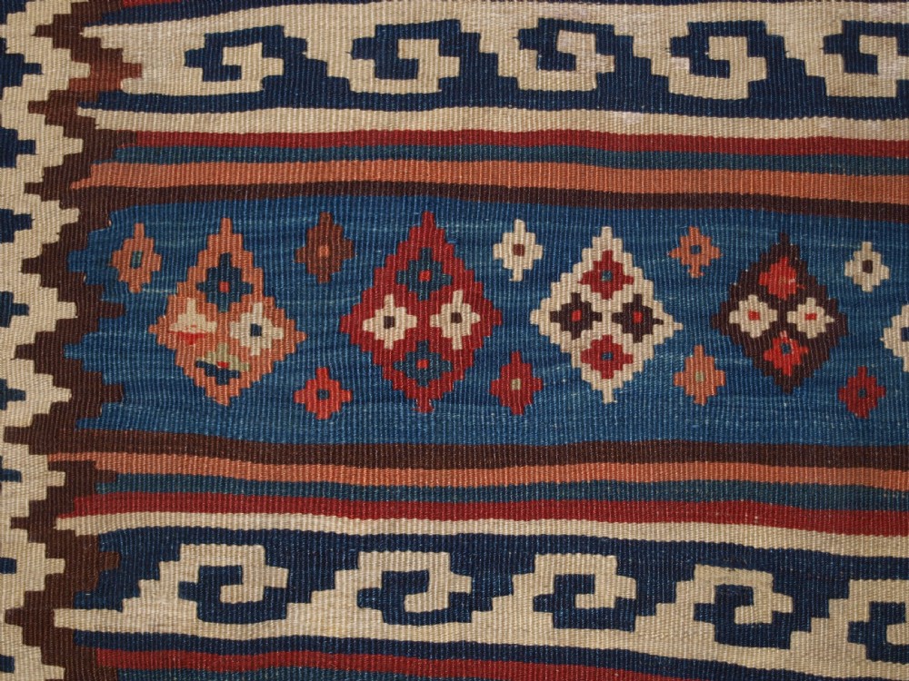 An antique handwoven Persian Varamin kilim rug featuring horizontal bands of blue, terracotta, and cream with repeating geometric diamond motifs. View XII