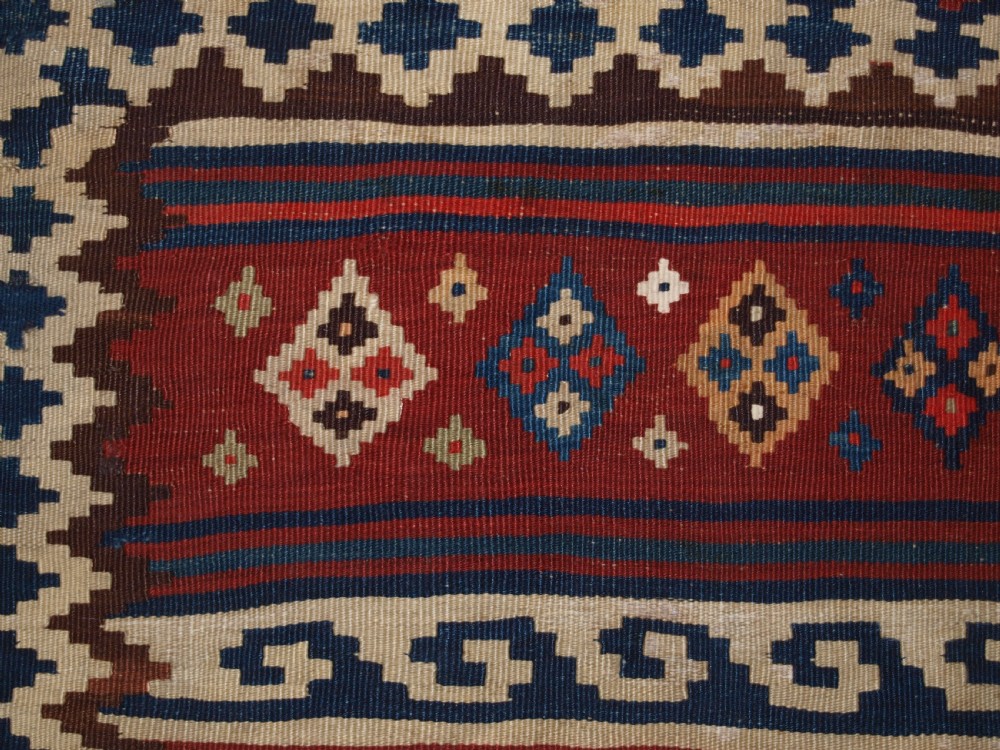 An antique handwoven Persian Varamin kilim rug featuring horizontal bands of blue, terracotta, and cream with repeating geometric diamond motifs. View XIII