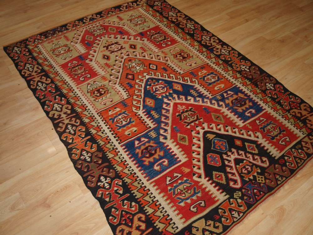 An antique Turkish Konya flatweave prayer kilim featuring a stepped mihrab pattern in red, blue, terracotta, and beige wool. View II