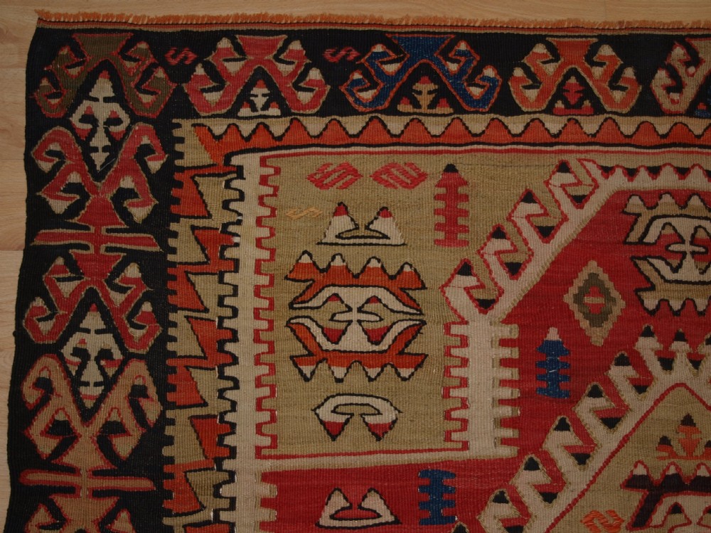 An antique Turkish Konya flatweave prayer kilim featuring a stepped mihrab pattern in red, blue, terracotta, and beige wool. View III