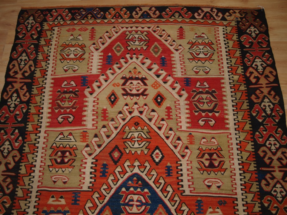 An antique Turkish Konya flatweave prayer kilim featuring a stepped mihrab pattern in red, blue, terracotta, and beige wool. View IV