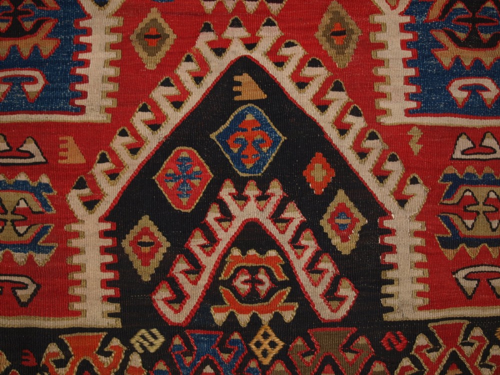 An antique Turkish Konya flatweave prayer kilim featuring a stepped mihrab pattern in red, blue, terracotta, and beige wool. View X