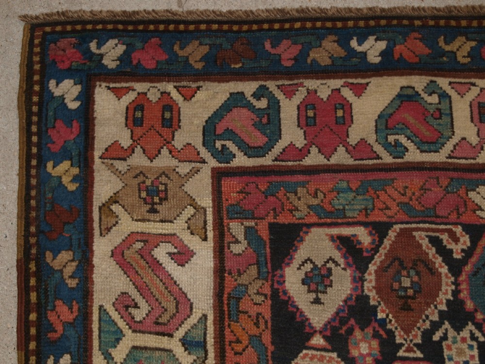 An antique 19th-century Caucasian Karabagh hallway runner carpet featuring colourful repeated boteh motifs across a dark central field framed by ivory geometric borders. View II