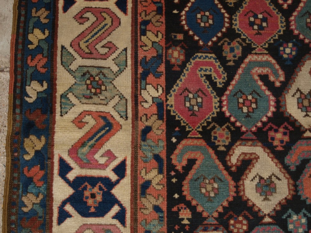 An antique 19th-century Caucasian Karabagh hallway runner carpet featuring colourful repeated boteh motifs across a dark central field framed by ivory geometric borders. View III