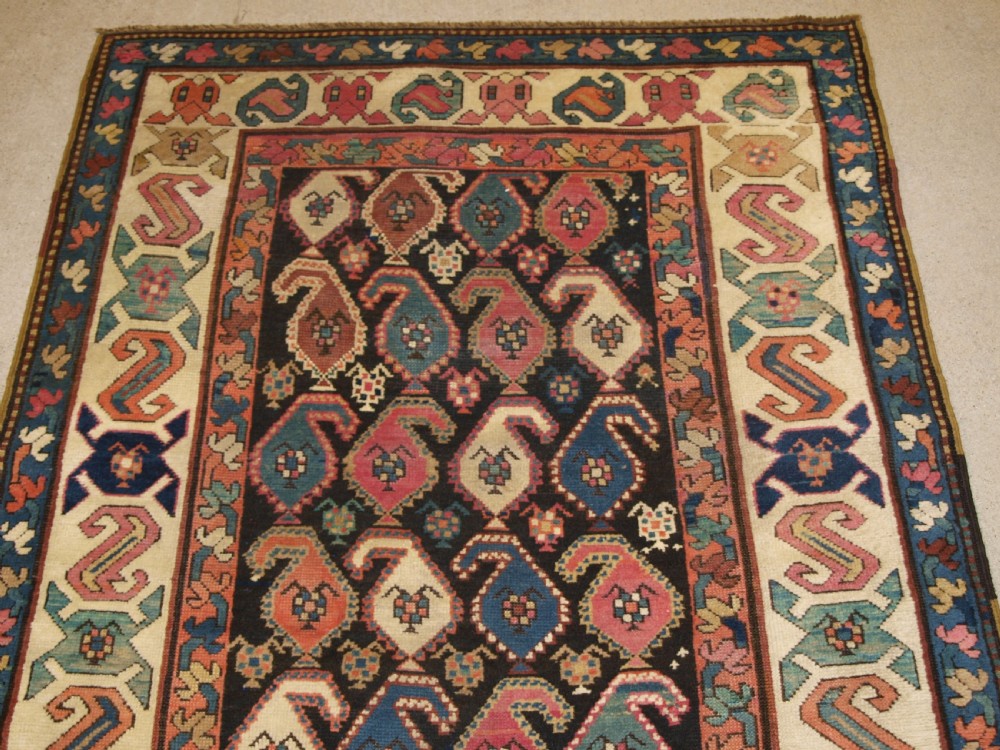 An antique 19th-century Caucasian Karabagh hallway runner carpet featuring colourful repeated boteh motifs across a dark central field framed by ivory geometric borders. View IV