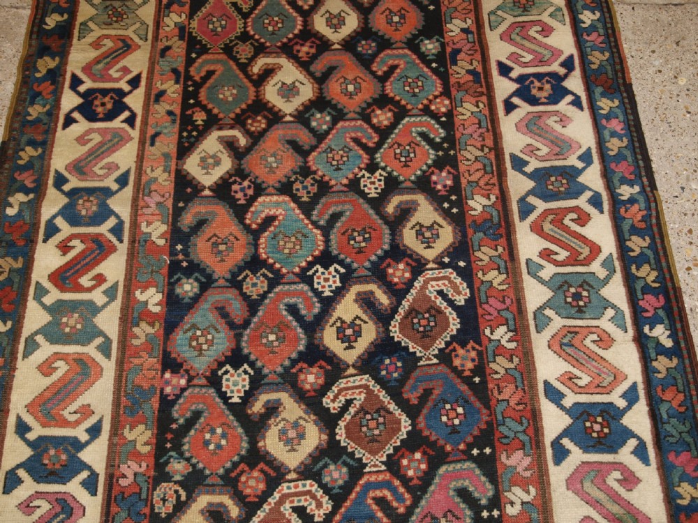 An antique 19th-century Caucasian Karabagh hallway runner carpet featuring colourful repeated boteh motifs across a dark central field framed by ivory geometric borders. View VI