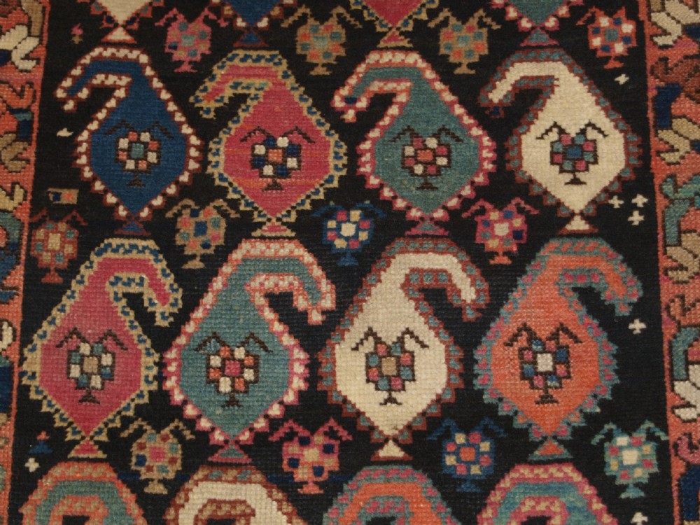 An antique 19th-century Caucasian Karabagh hallway runner carpet featuring colourful repeated boteh motifs across a dark central field framed by ivory geometric borders. View X