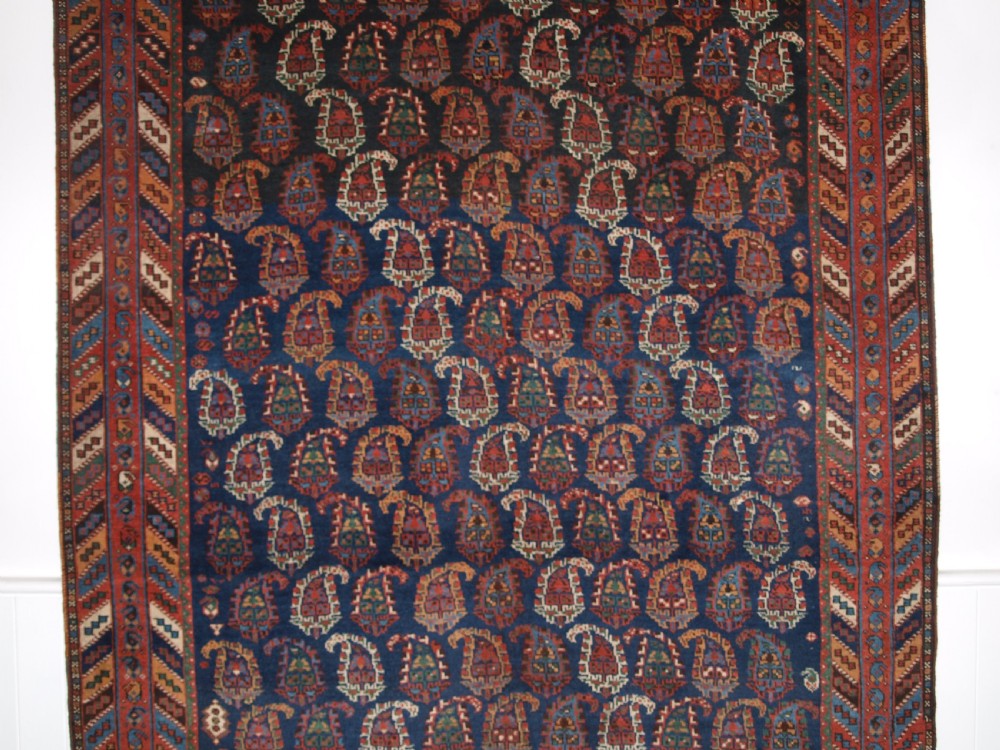 An antique Afshar long rug featuring a dark navy blue central field densely filled with repeating multi-coloured boteh motifs, bordered by geometric stripes. View III