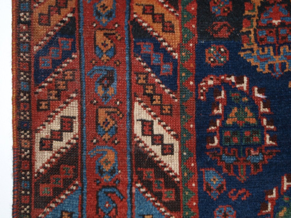 An antique Afshar long rug featuring a dark navy blue central field densely filled with repeating multi-coloured boteh motifs, bordered by geometric stripes. View VI