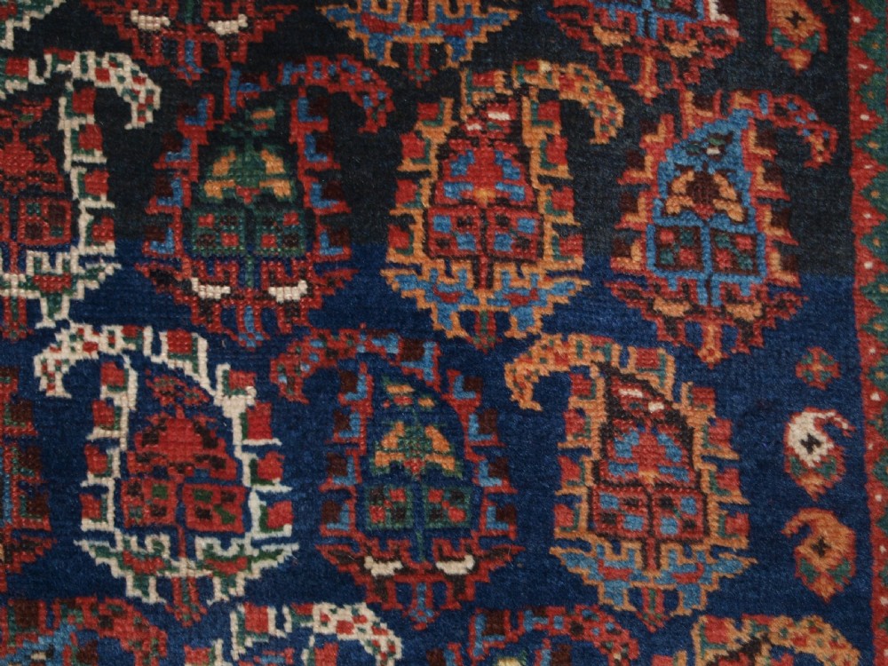 An antique Afshar long rug featuring a dark navy blue central field densely filled with repeating multi-coloured boteh motifs, bordered by geometric stripes. View IX