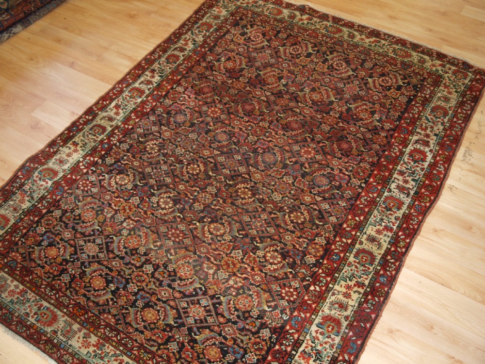 An antique hand-knotted Malayer rug displaying a detailed dark navy and red Herati lattice pattern framed by an ivory floral border. View III