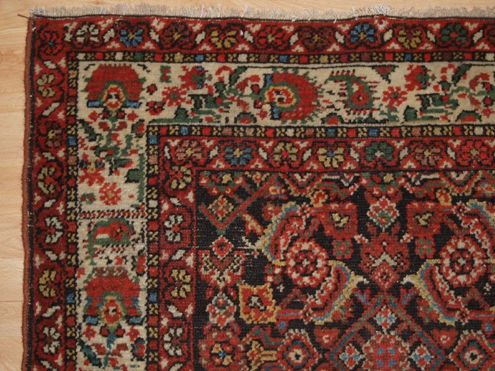 An antique hand-knotted Malayer rug displaying a detailed dark navy and red Herati lattice pattern framed by an ivory floral border. View IV