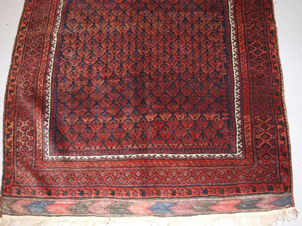 An antique hand-knotted Baluch prayer rug featuring a pointed mihrab arch motif, geometric lattice patterning, and a dark red and indigo colour palette. View VIII