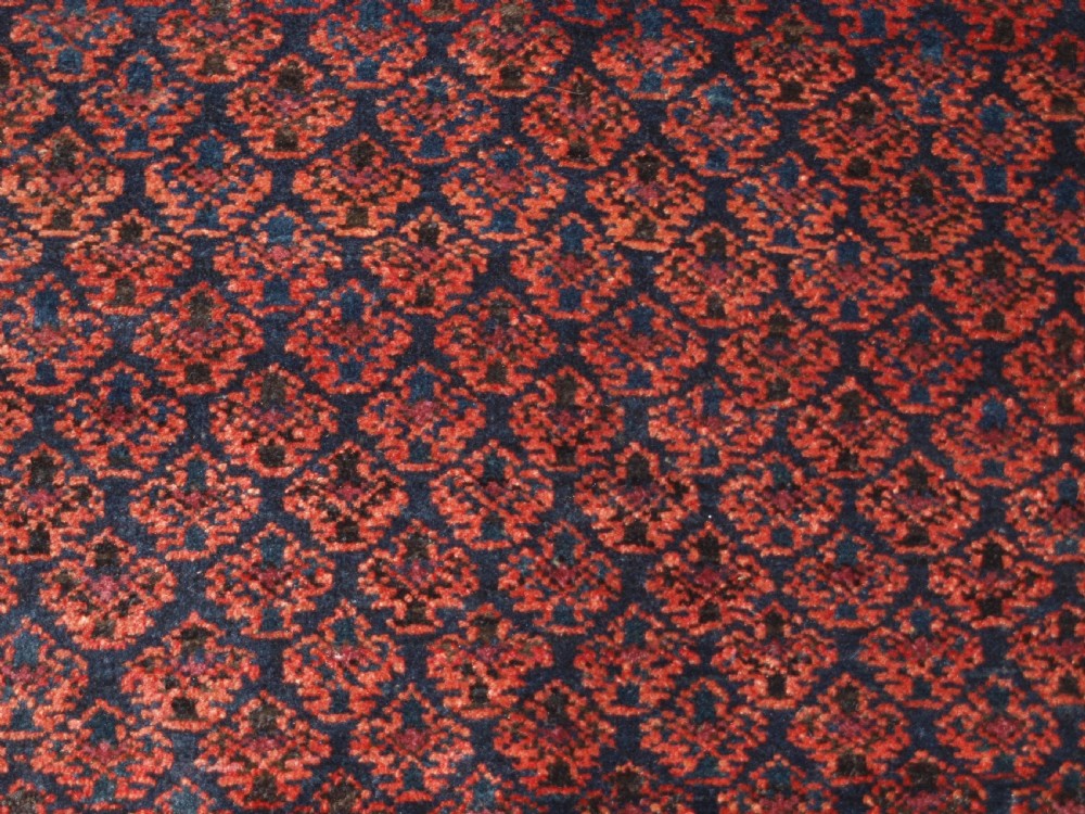An antique hand-knotted Baluch prayer rug featuring a pointed mihrab arch motif, geometric lattice patterning, and a dark red and indigo colour palette. View IX