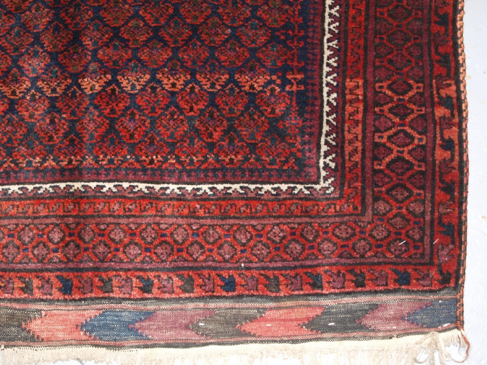 An antique hand-knotted Baluch prayer rug featuring a pointed mihrab arch motif, geometric lattice patterning, and a dark red and indigo colour palette. View XII