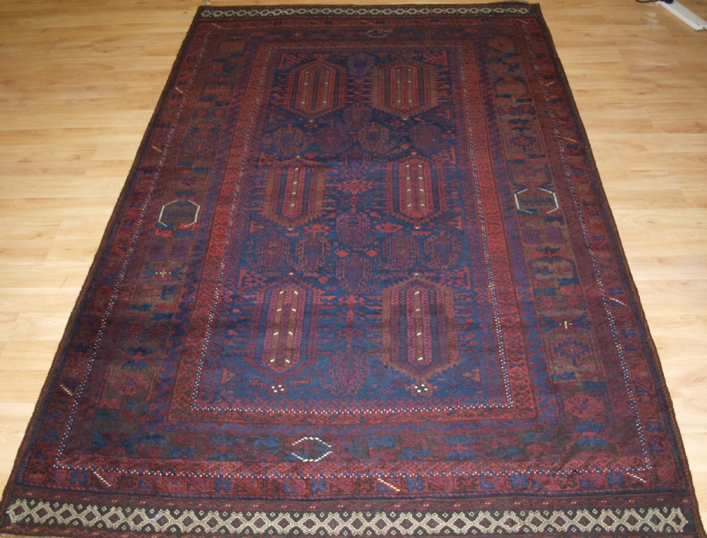 An antique hand-knotted wool carpet featuring deep blue and dark red geometric octagonal medallions inside layered decorative borders.