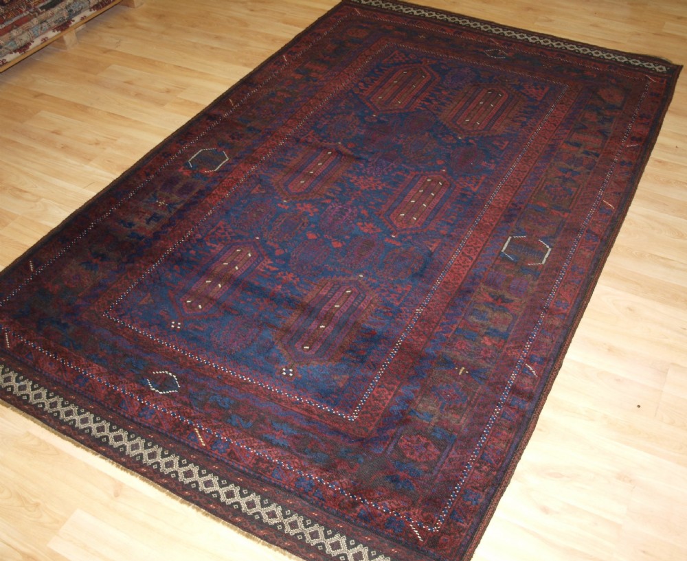 An antique hand-knotted wool carpet featuring deep blue and dark red geometric octagonal medallions inside layered decorative borders. View II