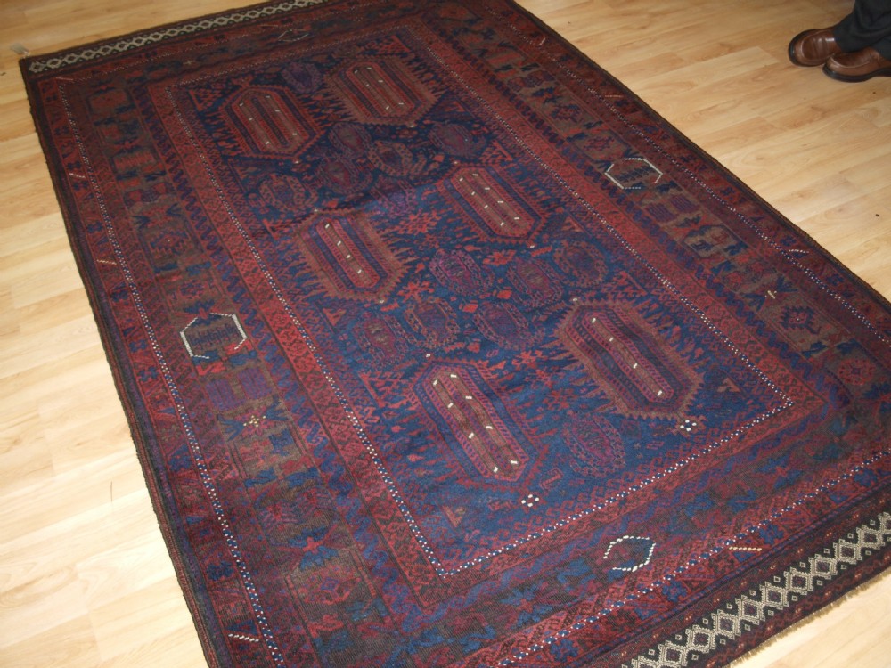 An antique hand-knotted wool carpet featuring deep blue and dark red geometric octagonal medallions inside layered decorative borders. View III