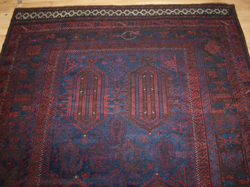 An antique hand-knotted wool carpet featuring deep blue and dark red geometric octagonal medallions inside layered decorative borders. View IV