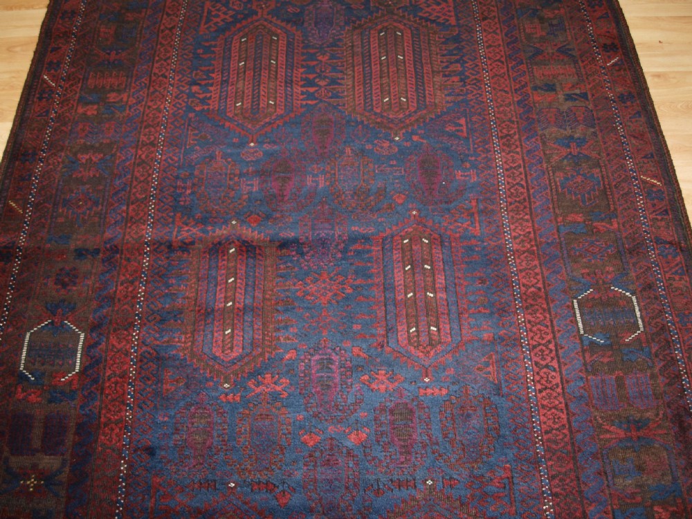 An antique hand-knotted wool carpet featuring deep blue and dark red geometric octagonal medallions inside layered decorative borders. View V