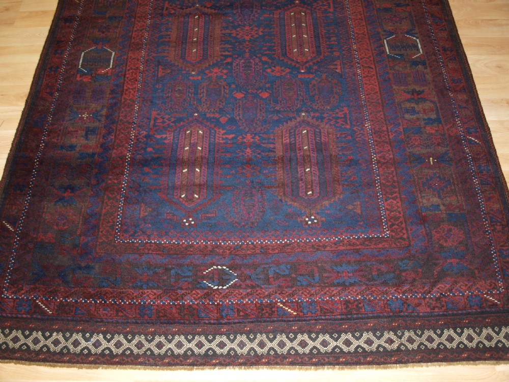 An antique hand-knotted wool carpet featuring deep blue and dark red geometric octagonal medallions inside layered decorative borders. View VI