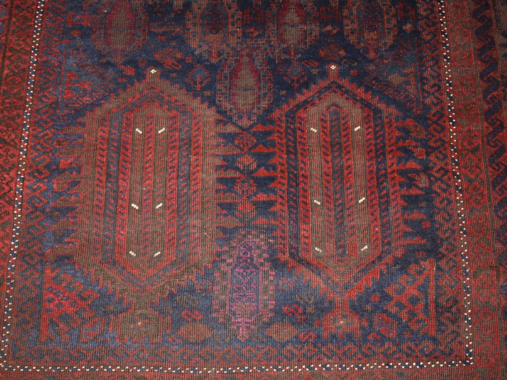 An antique hand-knotted wool carpet featuring deep blue and dark red geometric octagonal medallions inside layered decorative borders. View VII