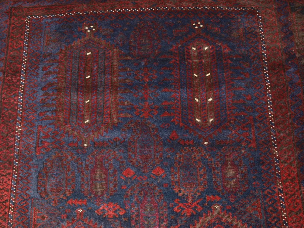 An antique hand-knotted wool carpet featuring deep blue and dark red geometric octagonal medallions inside layered decorative borders. View VIII