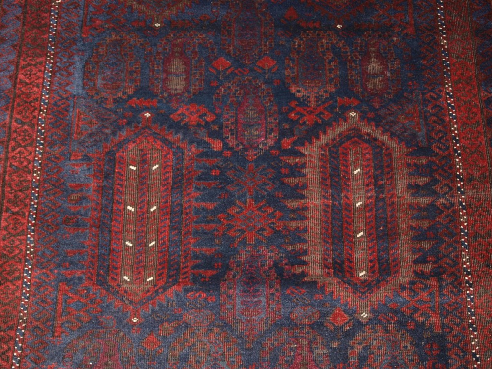 An antique hand-knotted wool carpet featuring deep blue and dark red geometric octagonal medallions inside layered decorative borders. View IX