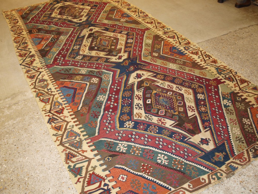 A late 19th-century handwoven Turkish Malatya kilim rug featuring complex geometric diamond medallions in terracotta red, navy blue, green, and cream wool. View II