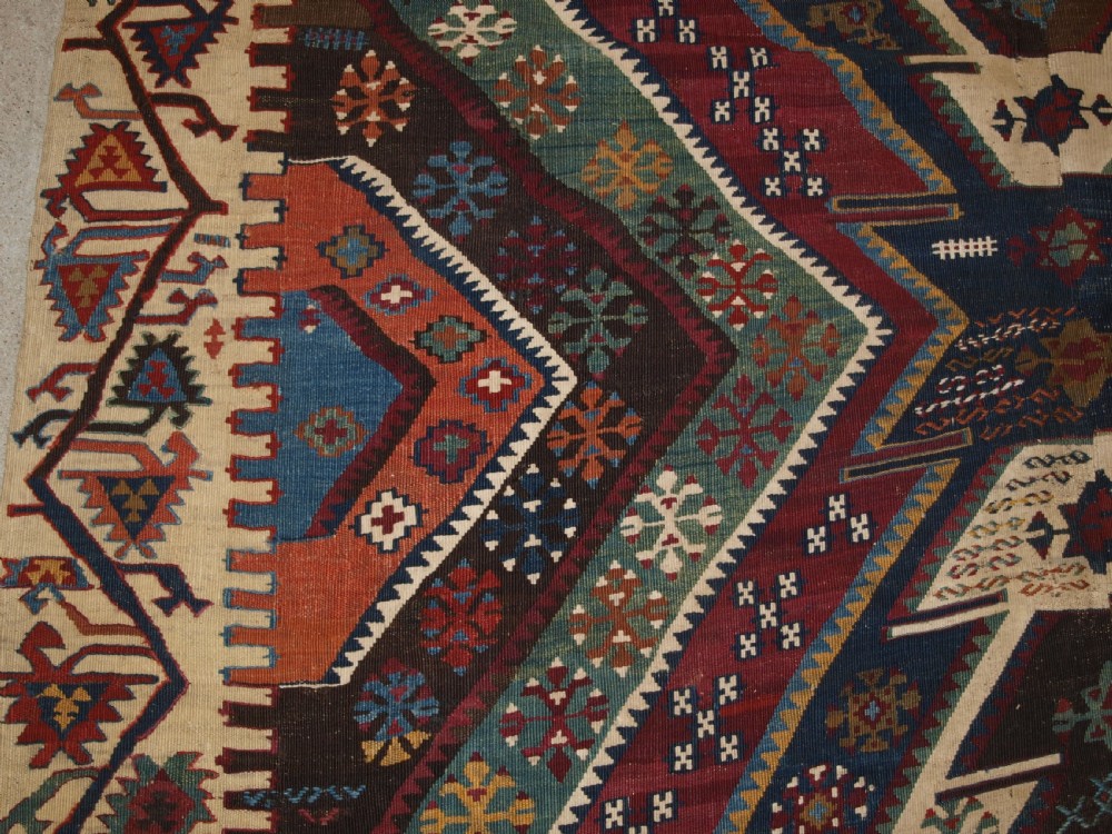 A late 19th-century handwoven Turkish Malatya kilim rug featuring complex geometric diamond medallions in terracotta red, navy blue, green, and cream wool. View IV