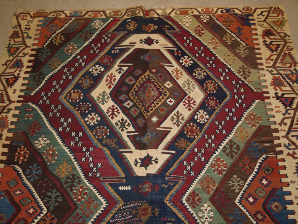 A late 19th-century handwoven Turkish Malatya kilim rug featuring complex geometric diamond medallions in terracotta red, navy blue, green, and cream wool. View V