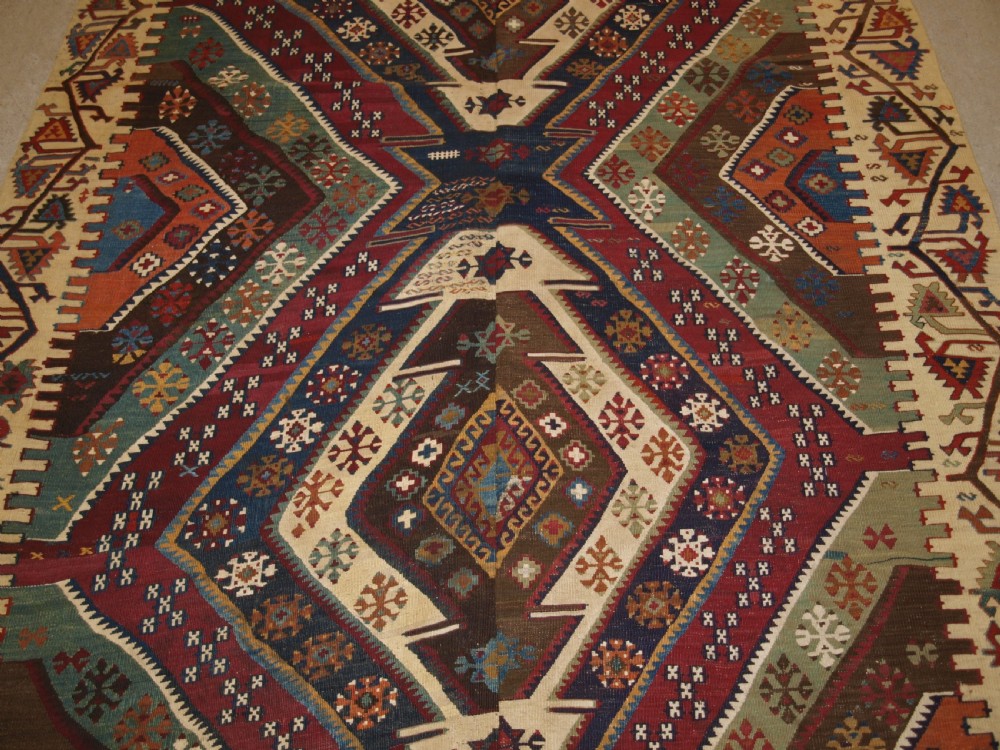 A late 19th-century handwoven Turkish Malatya kilim rug featuring complex geometric diamond medallions in terracotta red, navy blue, green, and cream wool. View VI