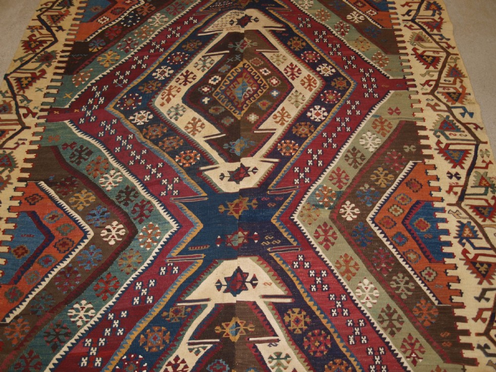 A late 19th-century handwoven Turkish Malatya kilim rug featuring complex geometric diamond medallions in terracotta red, navy blue, green, and cream wool. View VII