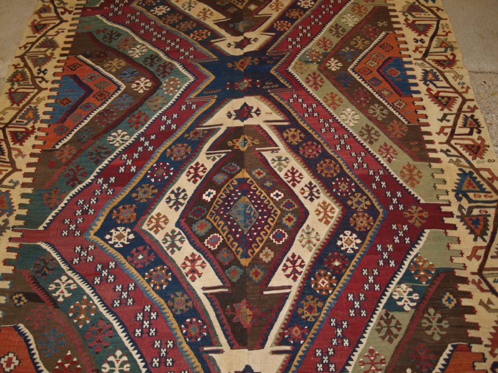 A late 19th-century handwoven Turkish Malatya kilim rug featuring complex geometric diamond medallions in terracotta red, navy blue, green, and cream wool. View VIII