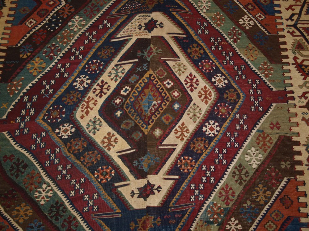 A late 19th-century handwoven Turkish Malatya kilim rug featuring complex geometric diamond medallions in terracotta red, navy blue, green, and cream wool. View IX