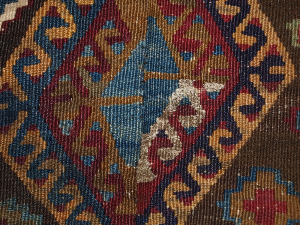 A late 19th-century handwoven Turkish Malatya kilim rug featuring complex geometric diamond medallions in terracotta red, navy blue, green, and cream wool. View XI
