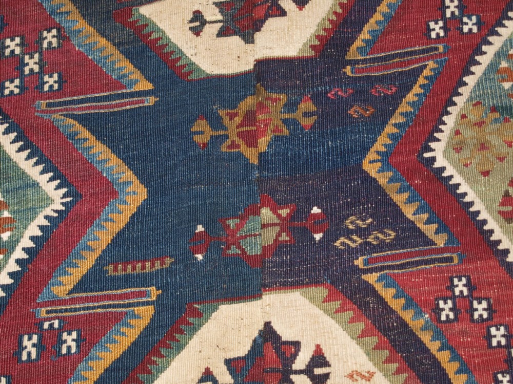 A late 19th-century handwoven Turkish Malatya kilim rug featuring complex geometric diamond medallions in terracotta red, navy blue, green, and cream wool. View XII