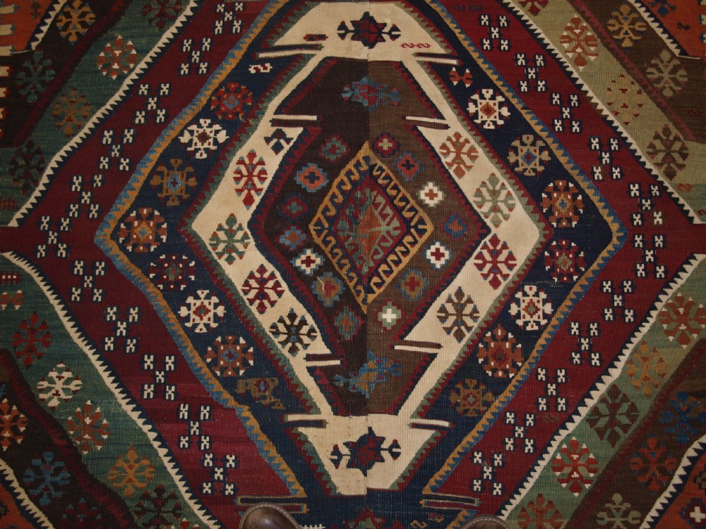 A late 19th-century handwoven Turkish Malatya kilim rug featuring complex geometric diamond medallions in terracotta red, navy blue, green, and cream wool. View XIII