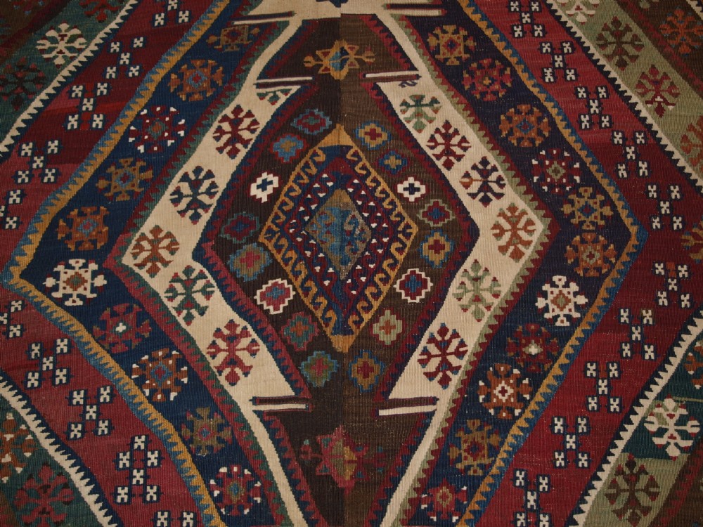 A late 19th-century handwoven Turkish Malatya kilim rug featuring complex geometric diamond medallions in terracotta red, navy blue, green, and cream wool. View XIV