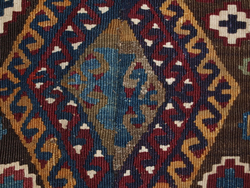 A late 19th-century handwoven Turkish Malatya kilim rug featuring complex geometric diamond medallions in terracotta red, navy blue, green, and cream wool. View XV