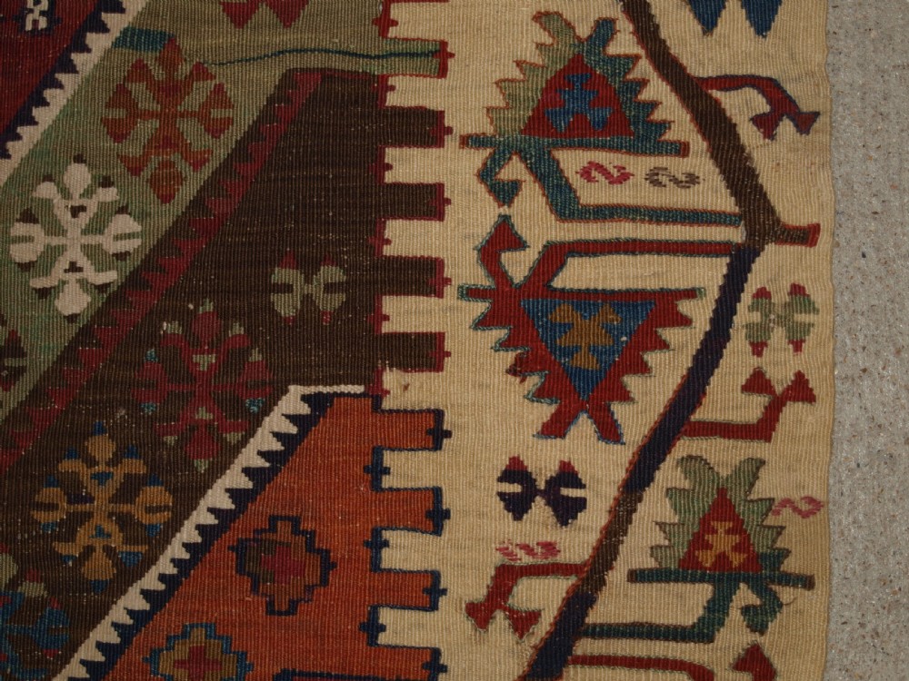 A late 19th-century handwoven Turkish Malatya kilim rug featuring complex geometric diamond medallions in terracotta red, navy blue, green, and cream wool. View XVI