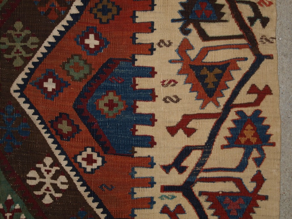 A late 19th-century handwoven Turkish Malatya kilim rug featuring complex geometric diamond medallions in terracotta red, navy blue, green, and cream wool. View XVII