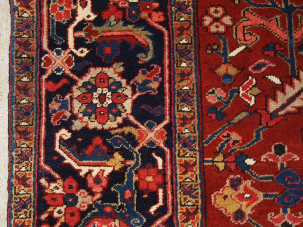 A large hand-knotted Persian Heriz carpet featuring a prominent geometric central medallion in dark navy and red, framed by cream spandrels and a wide dark border. View III