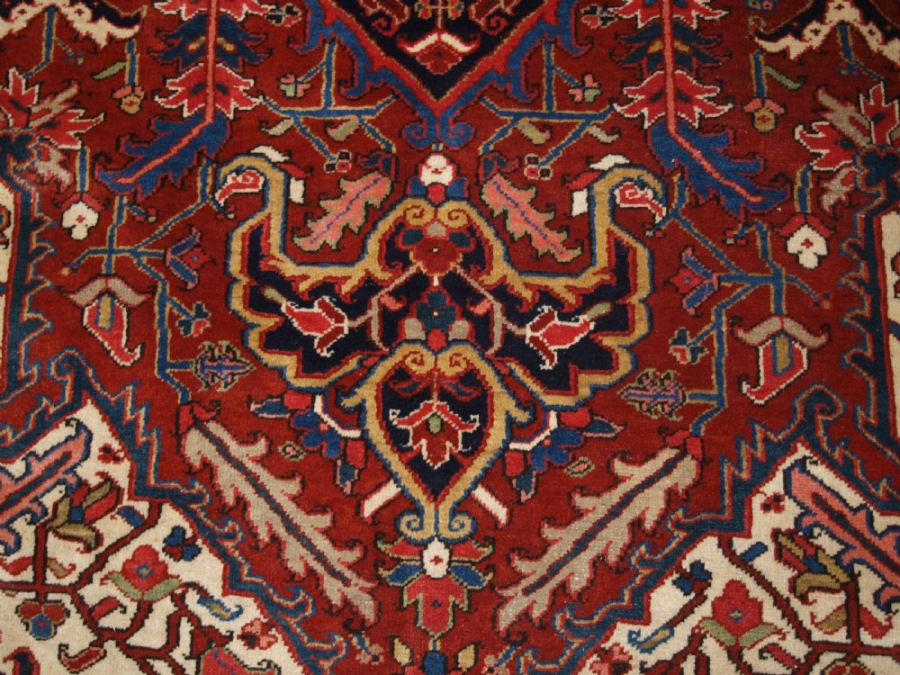 A large hand-knotted Persian Heriz carpet featuring a prominent geometric central medallion in dark navy and red, framed by cream spandrels and a wide dark border. View VIII